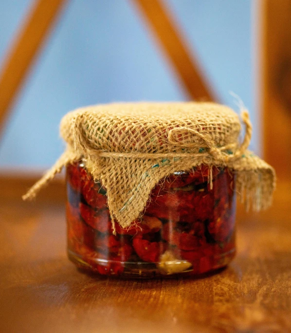 a jar filled with red berries on top of a table