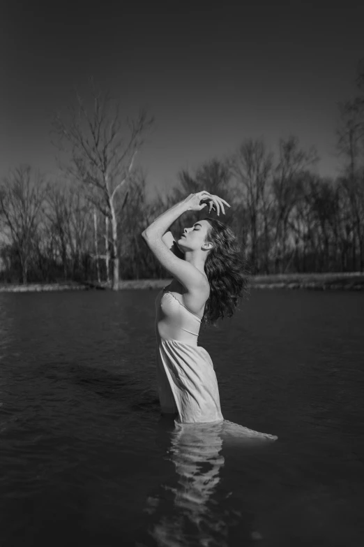 the woman is posing in the water wearing a swim suit