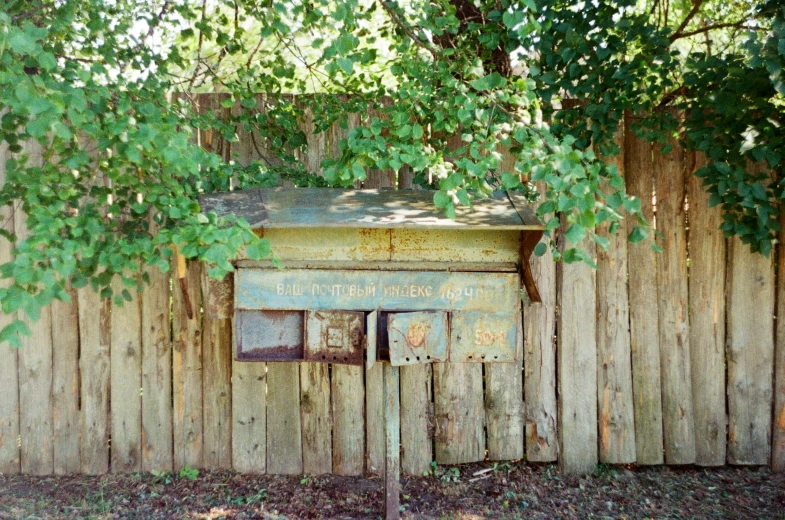 a rusty wooden shack sits in a field next to a fence