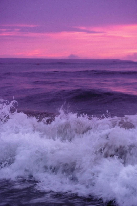 waves crash over an ocean beach as the sun sets