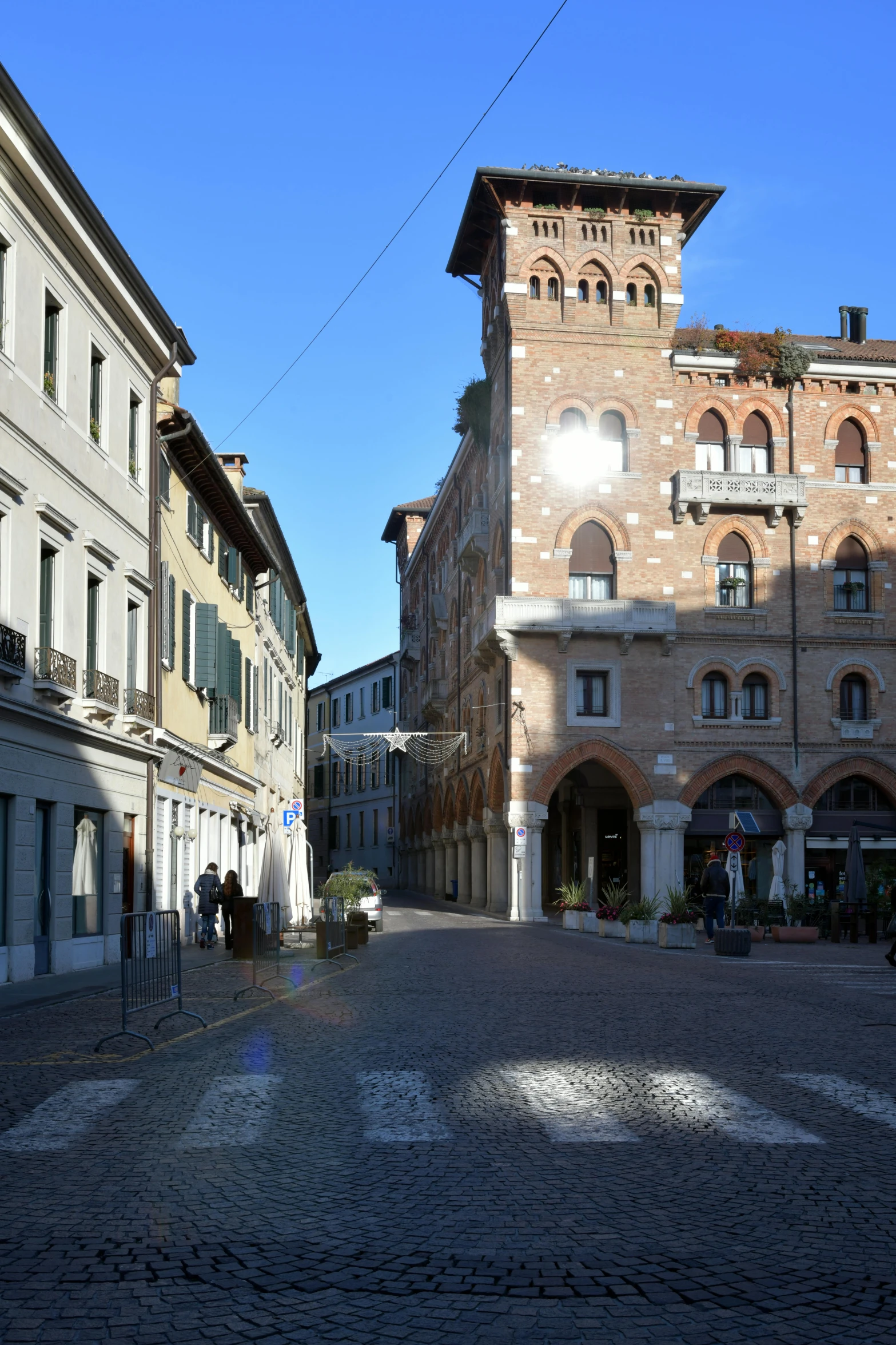 a small road with an old building on one side and people walking on another