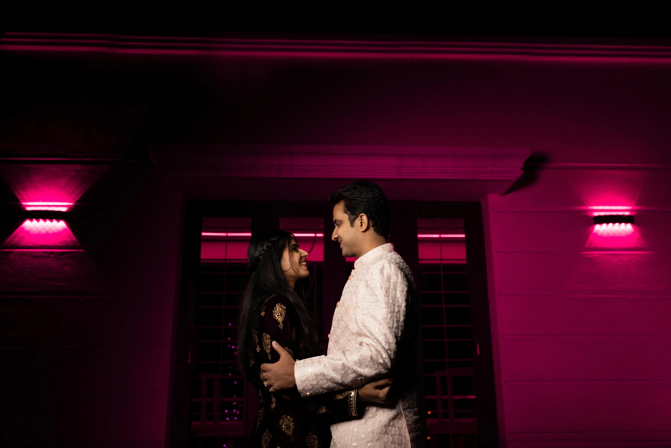 a man standing next to a woman under purple lights