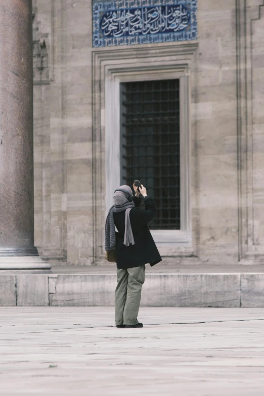 a man taking a picture of a tall stone building