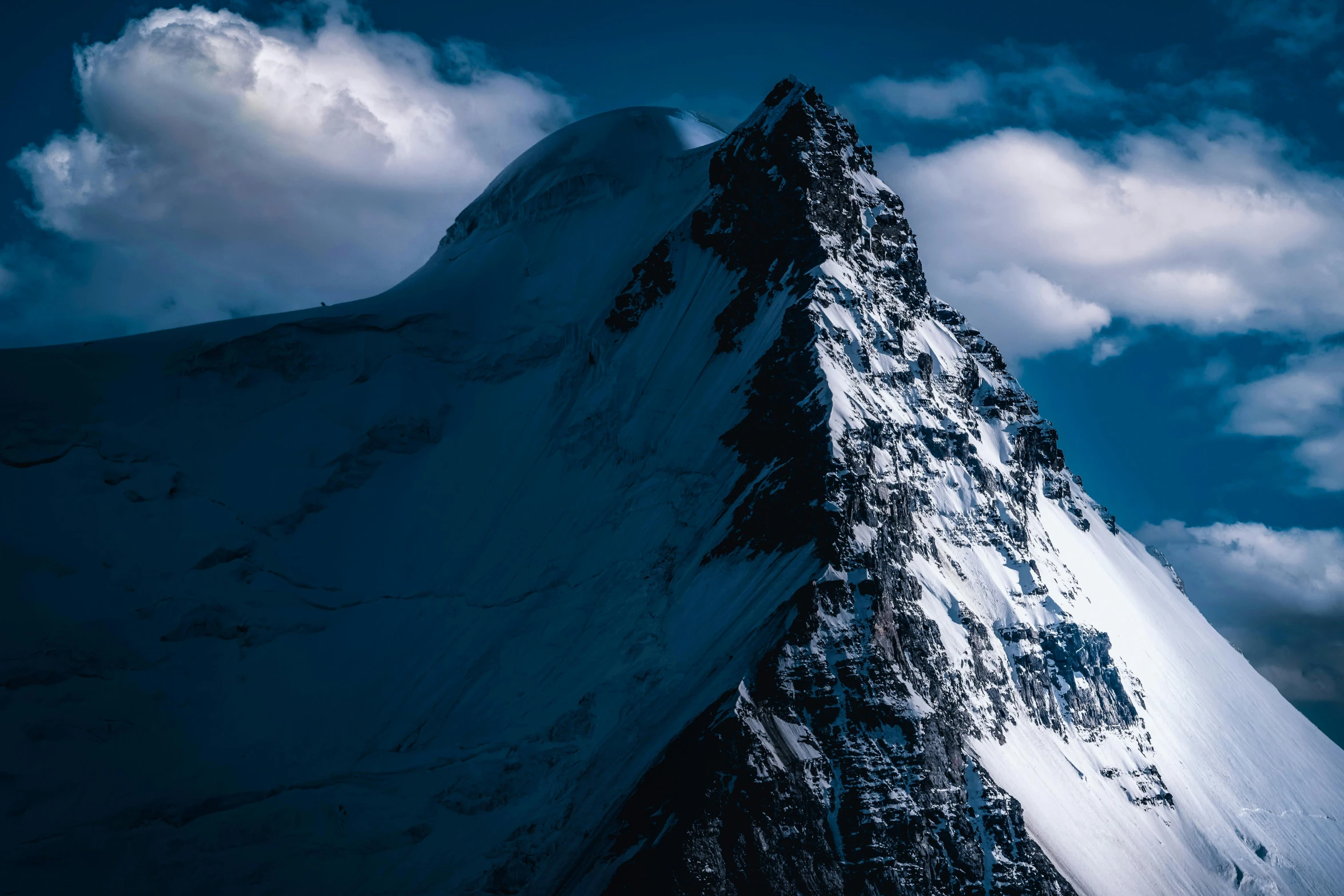 an extreme view of the top of a steep snow covered mountain