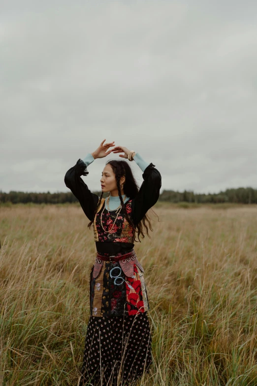 a girl standing in a field with her hand on top of her head