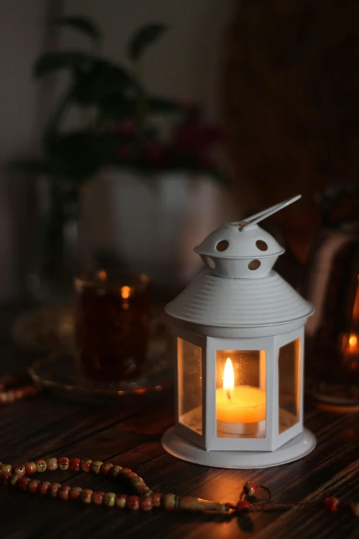 a white lantern on a table with beaded decorations