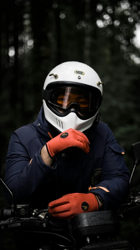 person in red gloves holding onto their white motorcycle helmet