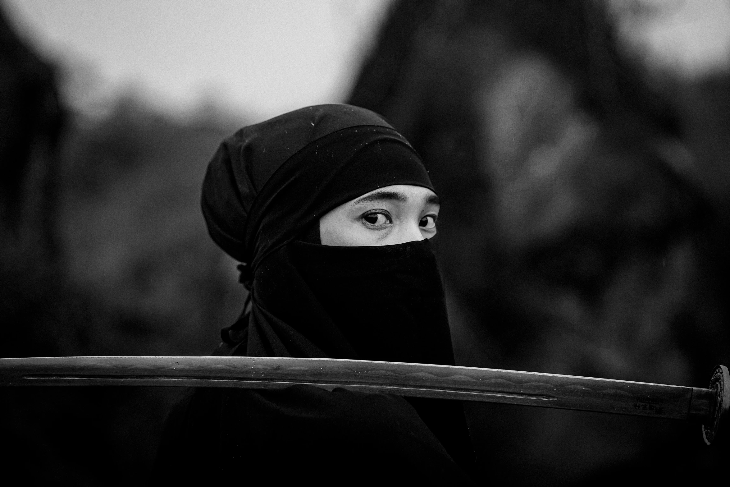 a person in black with a veil on and a sword to the side