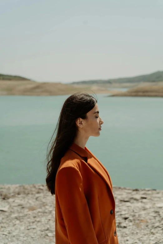 a woman looking off into the distance, wearing an orange jacket