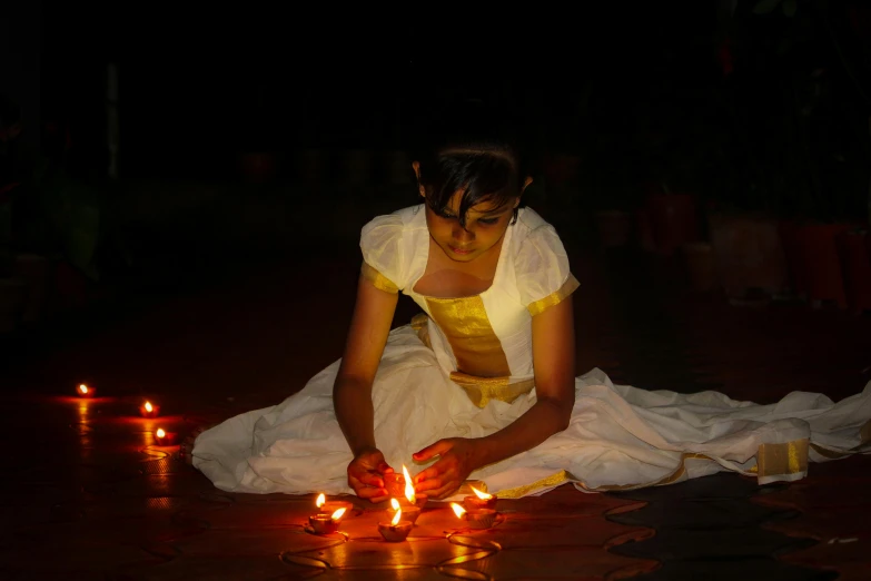 a young woman kneeling next to lighted candles