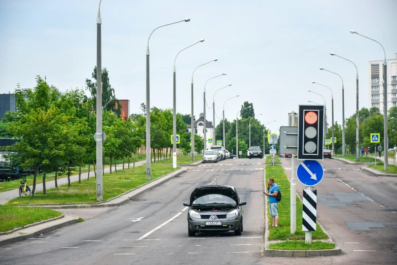 a person standing on a street corner by a car