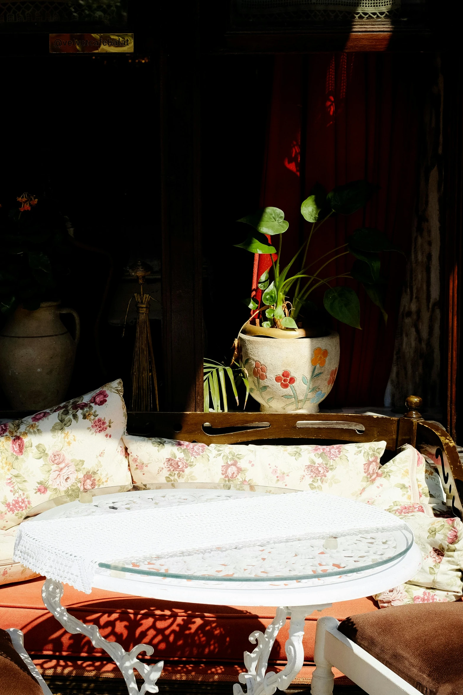 a white iron bench sitting under a plant in front of a mirror