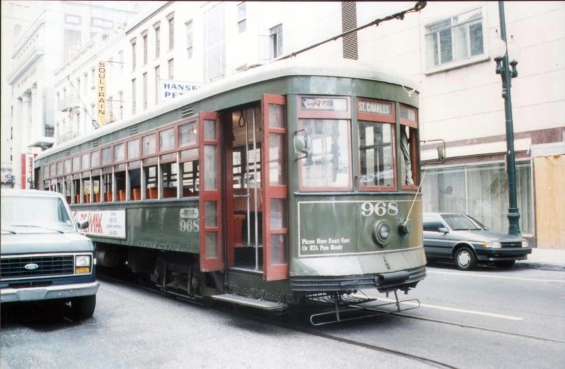 a green and red train is pulling two cars on the street