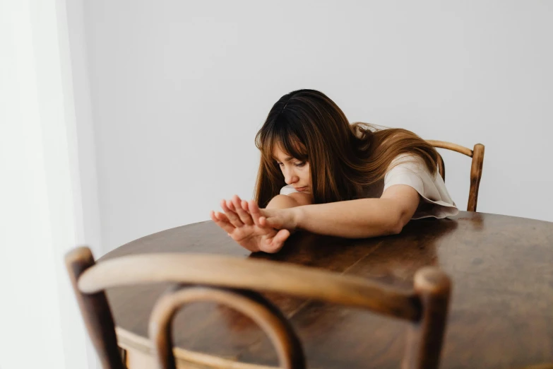 a woman sits at a wooden table looking at soing