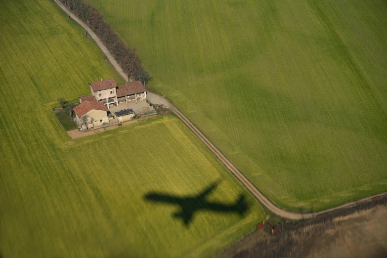 a plane flying over a large farm with some houses