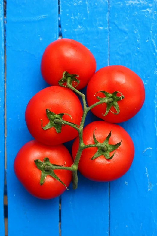 six tomatoes arranged on the stem of each other