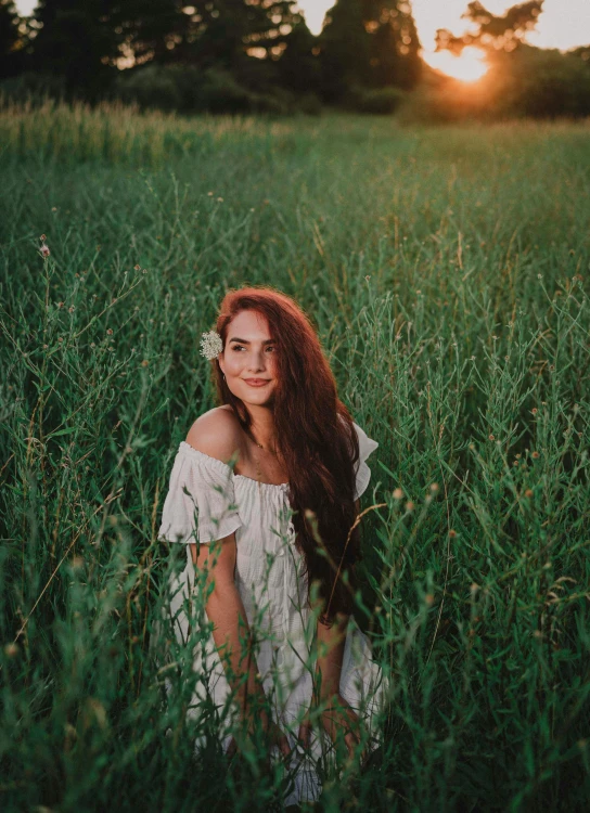 the girl stands in a green field with her hair up