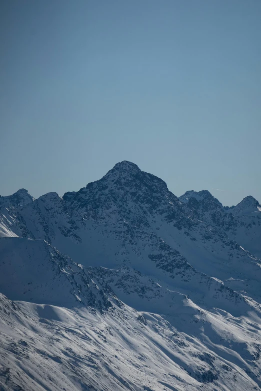 a snowy mountain range covered in snow under a blue sky