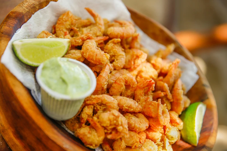 a wooden plate filled with fried food and a side of green sauce