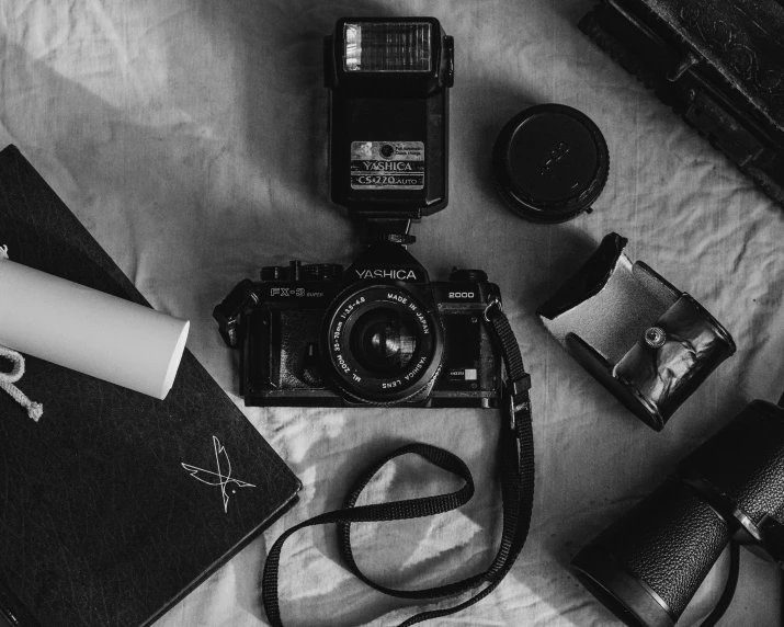 a small camera, some papers and other things sitting on top of a bed