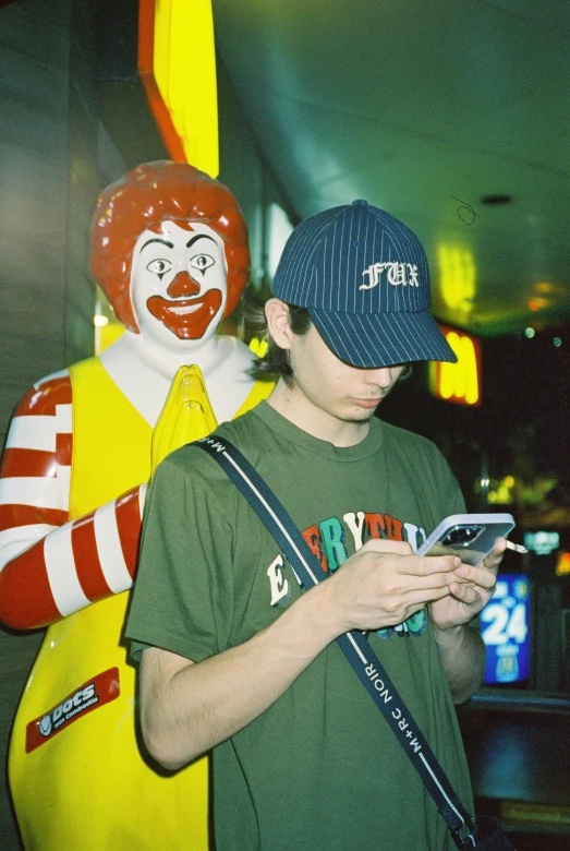 a boy in a green shirt holding a cellphone