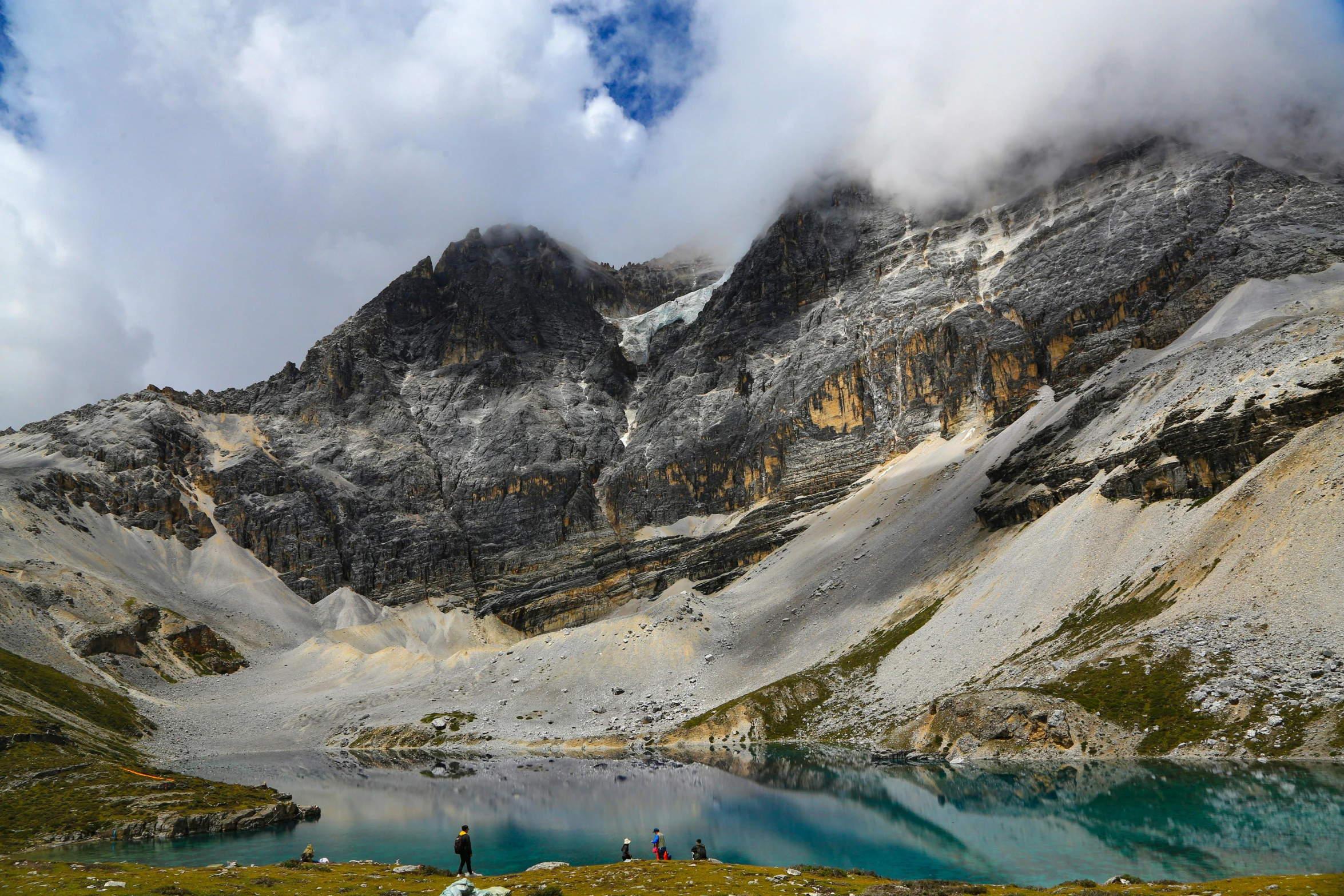 two people walk near a lake on top of a mountain