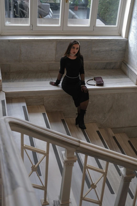 a woman in black is sitting on steps