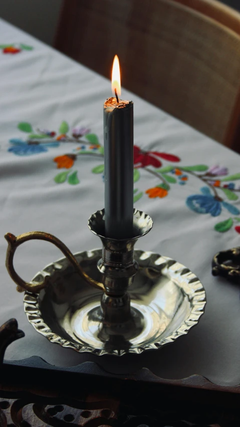 a lit candle is sitting on a decorative silver bowl