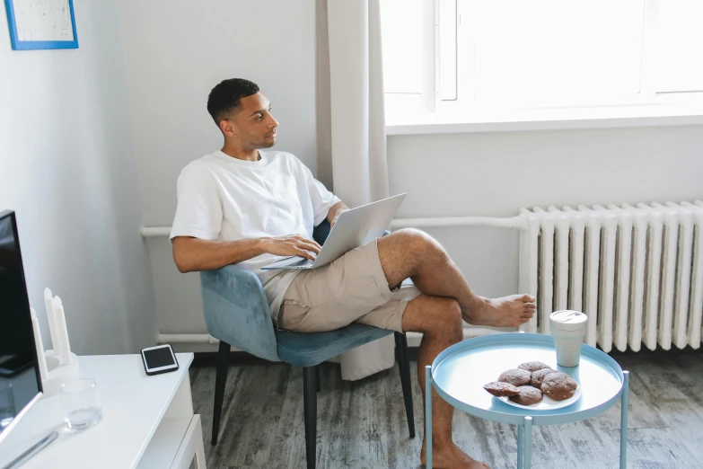 a man sitting in a chair looking at a laptop