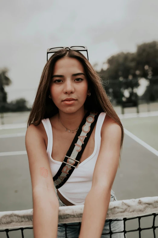 a girl leaning on the back of a tennis net