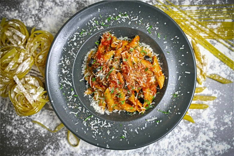 a grey plate containing some noodles and some sauce