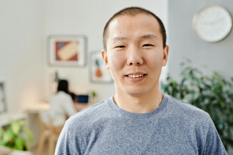 an asian man standing with a room in the background