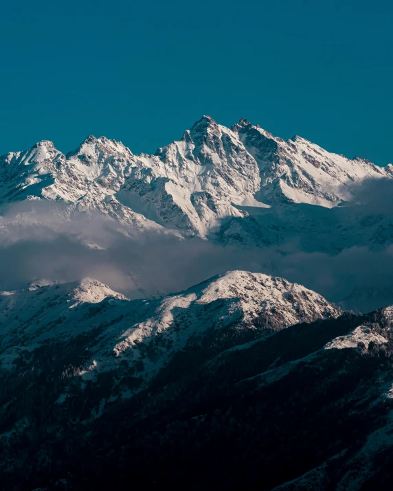 snow covered mountains at the top of a hill