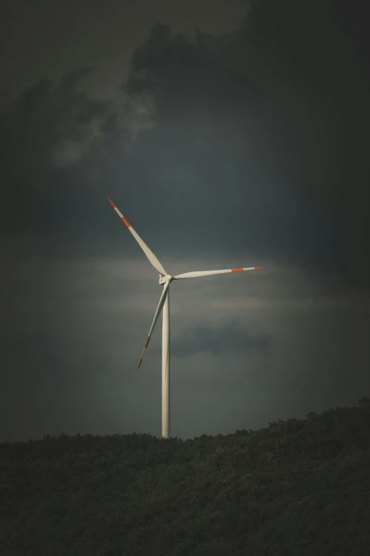 the tall wind turbines stand out against the dark cloudy sky