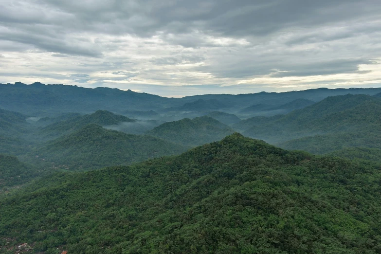 view over a mountain with large green hills in the background