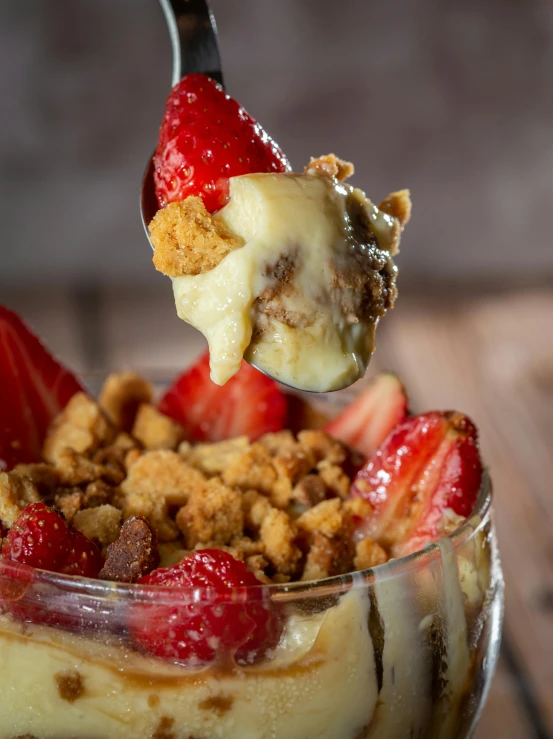 the spoon is full of dessert, with strawberries on top