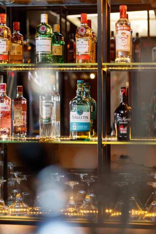 the shelf in the bar has various different bottles on it