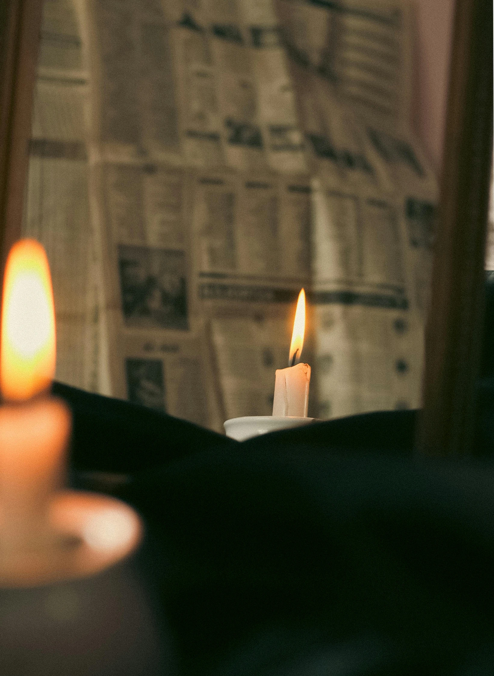 the reflection of two lit candles in a window