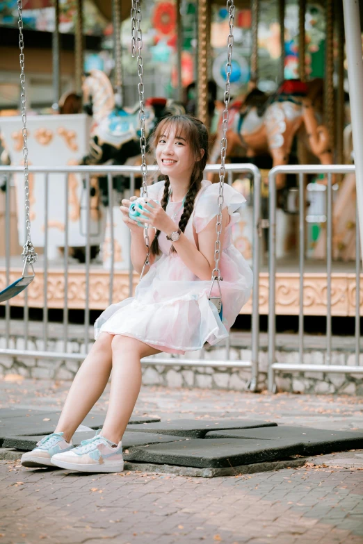 a small girl sitting on a swing at an amut park