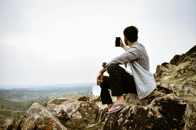 person sitting on large rocks using a camera