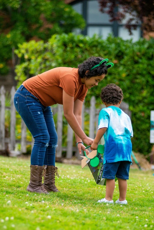 a woman holding a watering can and standing next to a  in a park