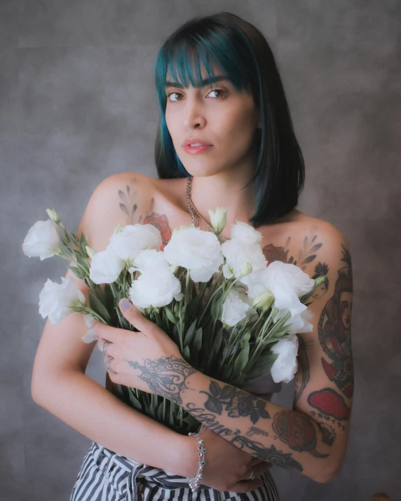 tattooed girl in striped skirt holding white flowers