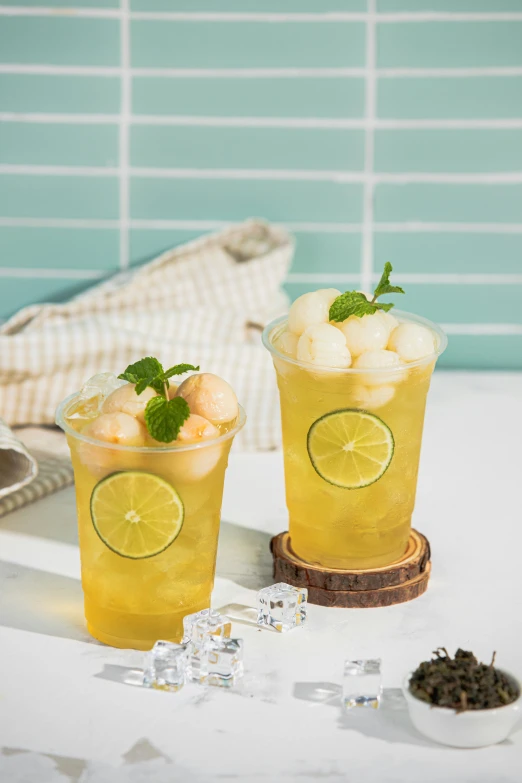 two glasses of lemon iced tea on top of a table