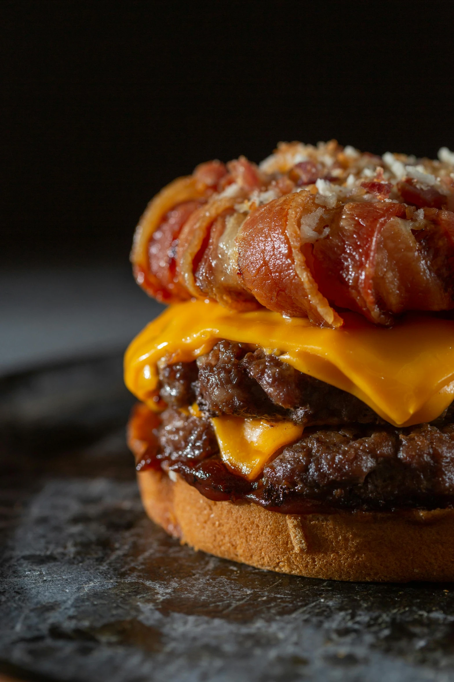 a bacon and cheese burger sitting on top of a black plate