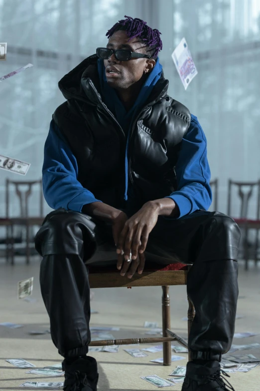 a man sitting on top of a chair wearing a leather jacket