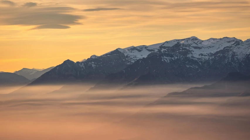 mountains and snow with clouds and sun shining