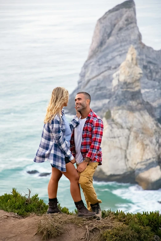 a man and woman posing on top of a cliff