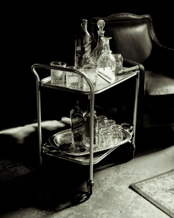 three clear glasses and bottles on a small metal tray