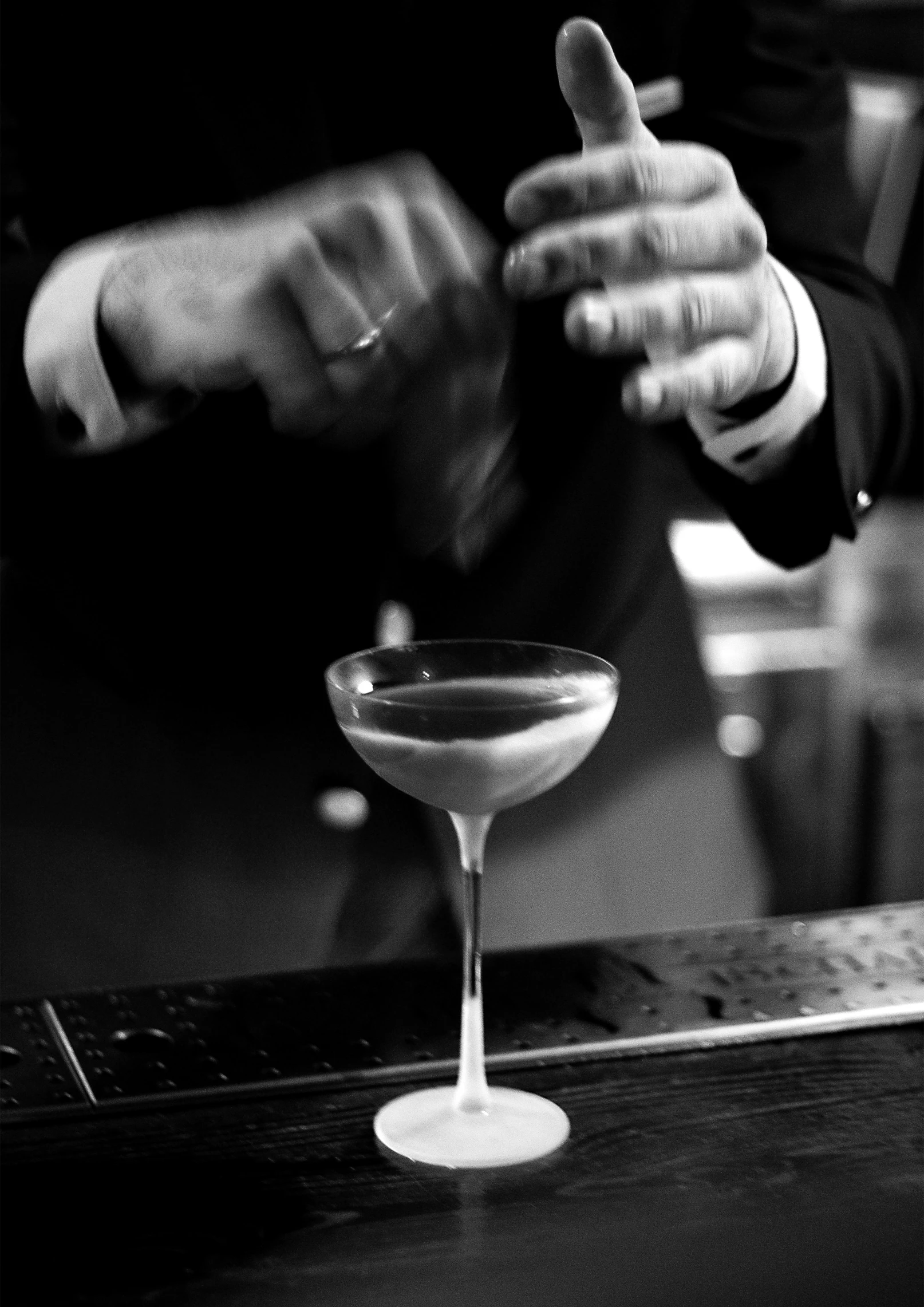 a man in a suit sitting at a bar with a cocktail glass