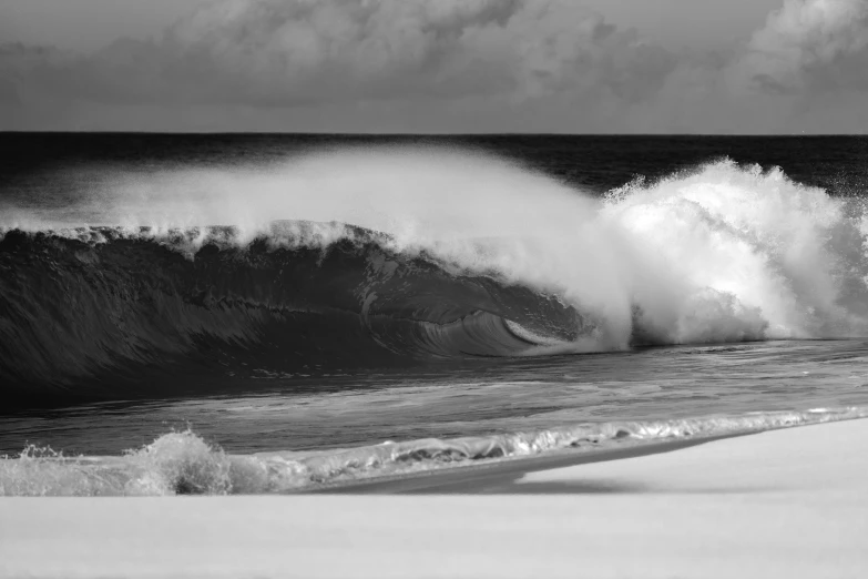 waves crashing in to the beach on a cloudy day